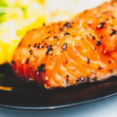 Un délicieux filet de saumon, assaisonné de poivre, prêt pour un barbecue de la mer. Accompagné d'une purée verte et jaune floue.
