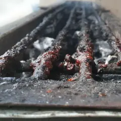 Grille de barbecue à charbon très sale, couverte de résidus de cuisson. Il est temps de nettoyer ce barbecue charbon pour la prochaine utilisation.