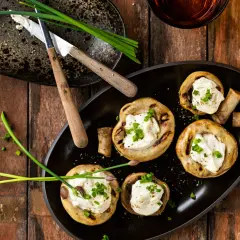 Champignons au barbecue farcis de fromage crémeux et garnis de ciboule fraîche. Un délice simple pour un repas estival.