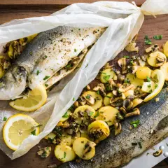 Deux bars en papillote au barbecue, accompagnés de pommes de terre et champignons, citron et persil.