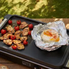Un camembert fondant à la plancha, entouré de poulet grillé et de tomates cerises. Un délice pour un repas en plein air.