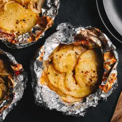 Pommes de terre en papillote, idéales pour un barbecue au gaz. Savoureuses et tendres, elles sont prêtes à être dégustées.