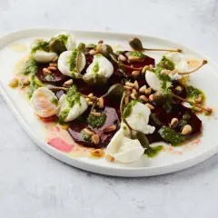 Salade de betterave fumée, mozzarella, pignons et câpres, arrosée d'une sauce verte.