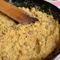 Préparation d'une recette de farine de maïs dans une poêle avec une spatule en bois.
