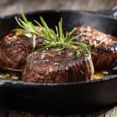 Trois tournedos saisis à la poêle, garnis de romarin frais. Une recette simple pour un plat savoureux.