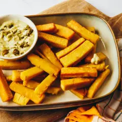 Assiette de panisses dorées et croustillantes, servies avec une sauce crémeuse aux herbes. Un délice à partager !