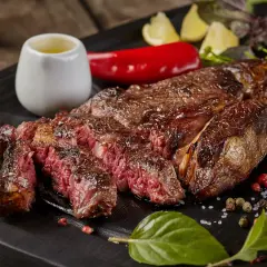 Une côte de bœuf parfaitement saisie, juteuse et rosée, prête pour la dégustation. La cuisson est idéale pour ce plat.