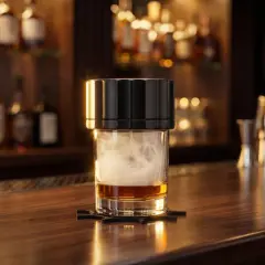Verre de whisky fumé, montrant comment fonctionne un fumoir à cocktail. Des bouteilles d'alcool en arrière-plan.
