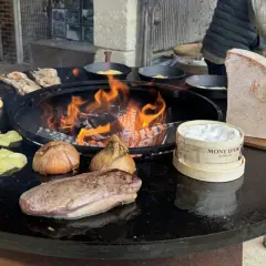 Préparation d'une recette brasero hiver : viande, pommes de terre, oignons, champignons et Mont d'Or fondent sur le feu.