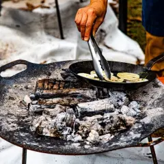 Cuisson de rondelles de lotus dans une poêle sur un feu de bois. La température du barbecue est parfaite pour cette cuisson.
