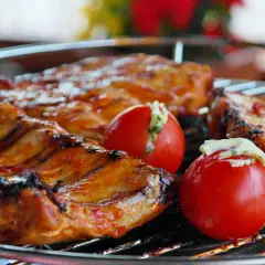 Côtelettes de porc grillées, savourant la qualité de la viande espagnole, accompagnées de tomates farcies.