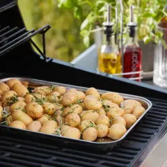 Un plateau de pommes de terre nouvelles assaisonnées d'herbes, prêtes pour le barbecue.