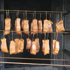 Filets de saumon suspendus dans un fumoir, prêts pour le fumage à froid. Le saumon est une excellente viande à fumer à froid.