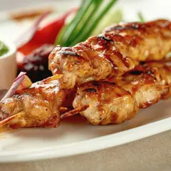 Délicieuse brochette de poulet grillée, servie avec une sauce verte et des légumes croquants. Un plat savoureux et coloré.