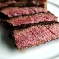Tranches de bœuf bleu blanc belge, juteuses et saignantes, sur une assiette blanche.