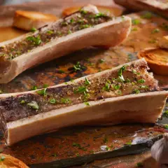 Os à moelle au barbecue, assaisonnés d'herbes et servis avec des toasts grillés et de l'ail. Un délice à savourer !