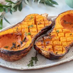 Butternut au barbecue, coupé en deux, grillé et parsemé de thym frais. La chair orangée est tendre et caramélisée.