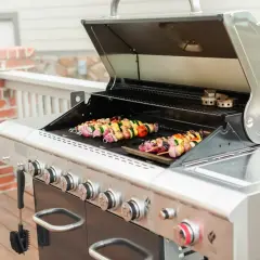 Brochettes colorées en cours de cuisson sur un barbecue à gaz. Les légumes et la viande sont prêts à être dégustés.