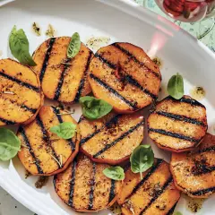 Tranches de courge au barbecue, grillées et assaisonnées, garnies de feuilles de basilic frais. Un délice estival !