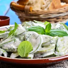 Salade fraîche de concombre à la crème, garnie de menthe et d'aneth. Parfait pour accompagner un concombre au barbecue.