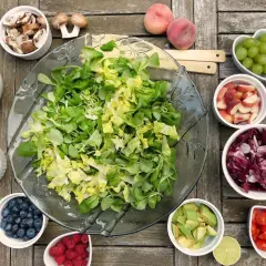 Préparation d'une salade barbecue : laitue, chou rouge, fraises, myrtilles, framboises, avocat, tomates cerises, pêches, raisins, noix de cajou, champignons et chou vert.