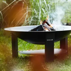 Un brasero Barbecook est prêt à allumer, avec des flammes dansantes et de la fumée s'élevant dans l'air.