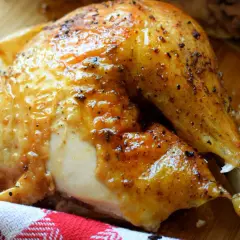 Un délicieux demi poulet BBQ, la peau dorée et brillante, prêt à être dégusté.