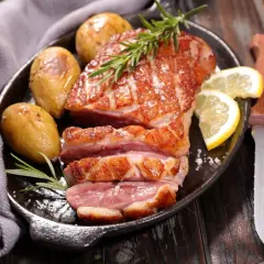 Un délicieux magret de canard au barbecue, servi avec des pommes de terre rôties, du romarin et des quartiers de citron.