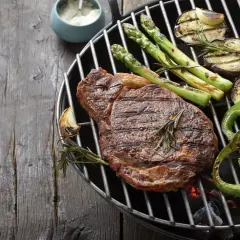 Un steak savoureux, des asperges, des aubergines et des poivrons verts sur un barbecue. Parfait pour savoir que faire cuire au barbecue.