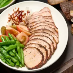 Tranches de longe de porc fumé, accompagnées de haricots verts, tomates, cornichons et oignons. Un délice fumé à savourer.