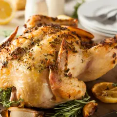 Un poulet entier au barbecue, doré et savoureux, garni d'herbes et de quartiers de citron grillés. Un délice pour les papilles !