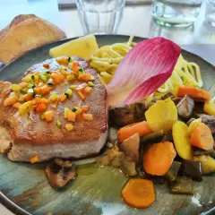 Pavé de thon poêlé, garni de dés de légumes croquants, servi avec des pâtes, des légumes racines et une feuille de chicorée. Une recette savoureuse.