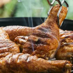 Des pilons de poulet grillés, savamment préparés avec une marinade pilon de poulet barbecue, dégagent une fumée appétissante sur le barbecue.