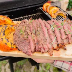 Un steak grillé et des quartiers de potimarron barbecue, servis sur une planche en bois.