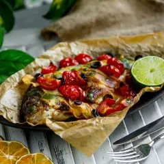 Dorade en papillote au barbecue, garnie de tomates cerises, olives et citron vert. Le temps de cuisson est parfait pour ce plat savoureux.