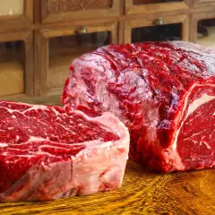 Deux pièces de viande rouge vif, un steak épais et un rôti, sur une planche en bois. Ce filet de bœuf promet un repas savoureux.