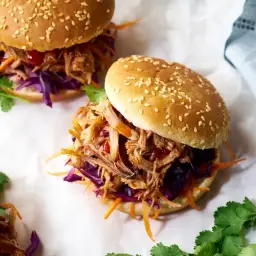Délicieux burger effiloché de porc, garni de chou rouge et carottes râpées, sur un pain aux graines de sésame.