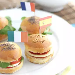 Mini pains burgers décorés de drapeaux européens : France, Irlande, Espagne, Suède. Parfait pour un apéritif festif !
