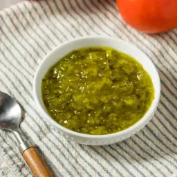 Un bol de sauce relish verte, prêt à être dégusté avec une cuillère.
