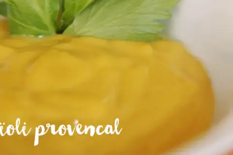 Un bol de crémeux aioli provençal, garni d'une feuille verte fraîche.