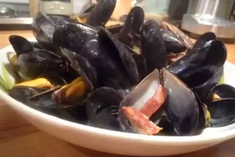 Un plat de moules poulette, fumantes et appétissantes, garnies de lardons croustillants. Un délice à partager.