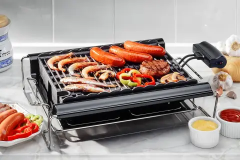 Un barbecue de table électrique avec crevettes, saucisses, steak, poivrons et champignons. Parfait pour un repas convivial.