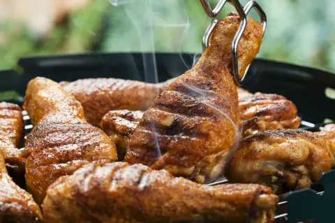 Des pilons de poulet grillés, savamment préparés avec une marinade pilon de poulet barbecue, dégagent une fumée appétissante sur le barbecue.
