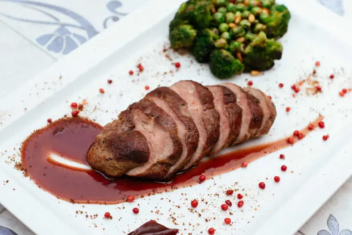 Tranches de filet mignon, parfaitement saisies, nappées d'une sauce rouge intense. Accompagné de brocolis et de petits pois. La cuisson du filet mignon est un art.