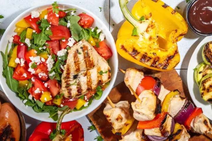 Une salade verte fraîche avec poulet grillé, tomates, poivrons et fromage. Accompagnée de brochettes, courgettes grillées et saucisses.