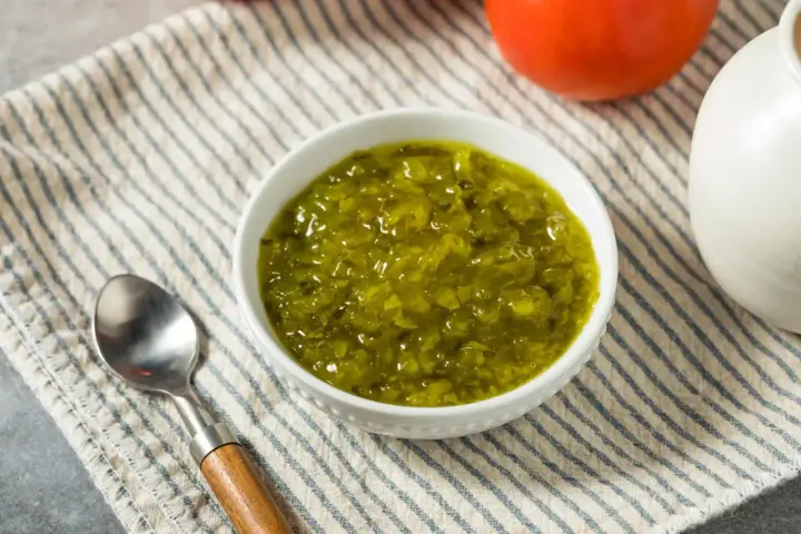 Un bol de sauce relish verte, prêt à être dégusté avec une cuillère.