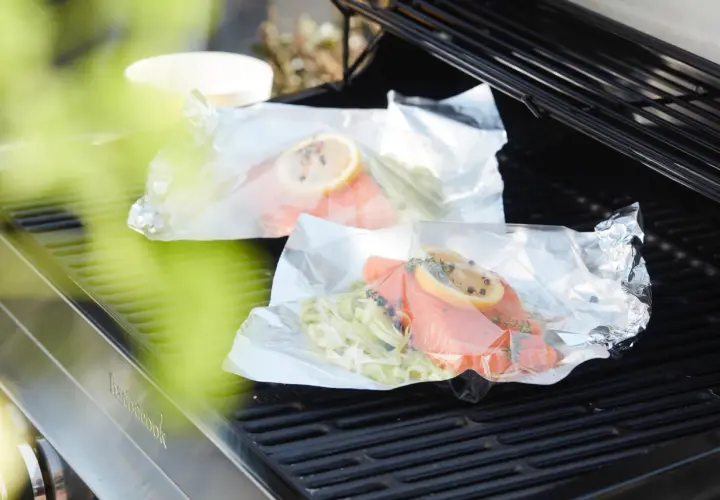 Deux papillotes de saumon en préparation sur un barbecue, prêtes à être cuites.