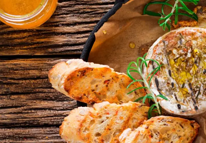 Un délicieux fromage au barbecue, doré et fondant, servi avec du pain grillé et du romarin frais.