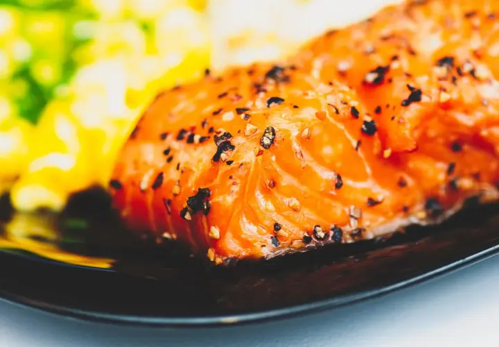 Un délicieux filet de saumon, assaisonné de poivre, prêt pour un barbecue de la mer. Accompagné d'une purée verte et jaune floue.