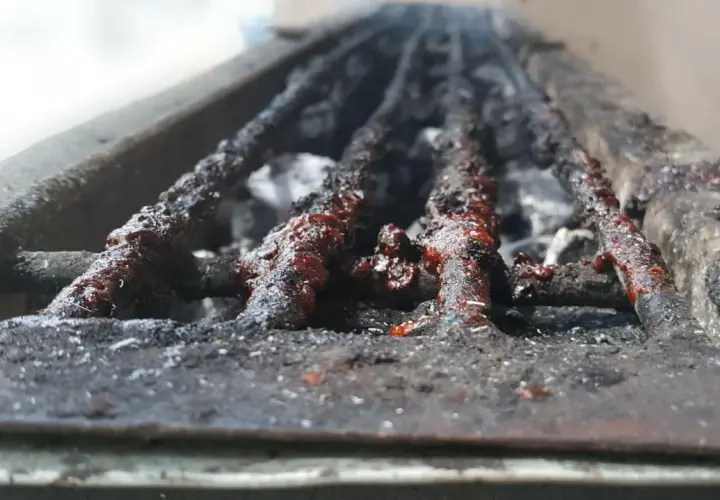 Grille de barbecue à charbon très sale, couverte de résidus de cuisson. Il est temps de nettoyer ce barbecue charbon pour la prochaine utilisation.